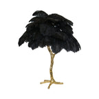 Clérachic table lamp with black ostrich feathers on a gold branch stem with splayed feet, on a white background.