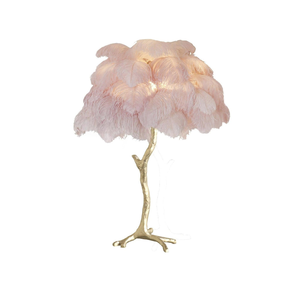 Clérachic table lamp with lit blush-pink feathers on a gold branch stem with splayed feet, on a white background.