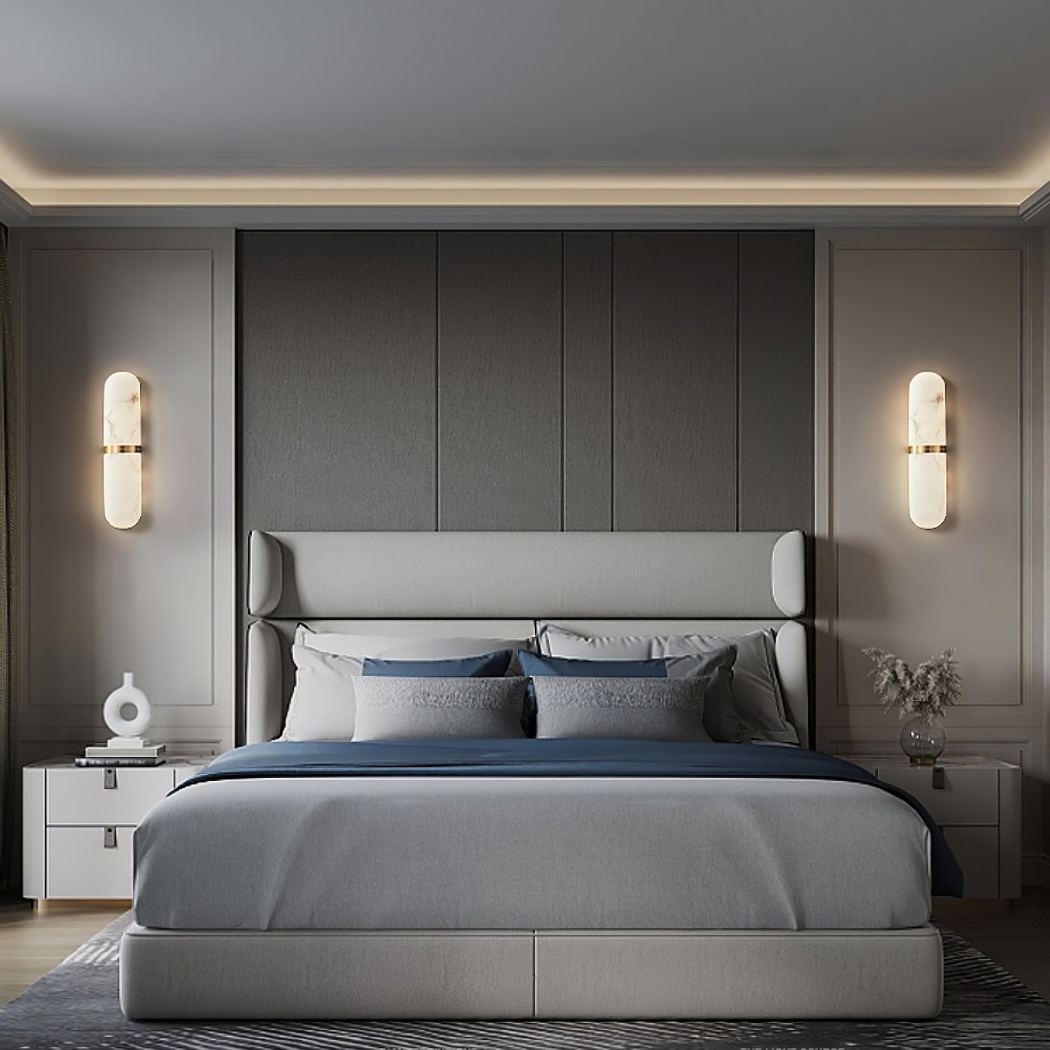 Clérachic pill sconce mounted on a panelled charcoal wall beside a low bed in a calm grey bedroom.