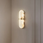 The Clérachic Ostruvyd alight on a plain warm-white wall beside a door casing, brass band glinting.