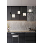 Clérachic box chandelier hung along a dark kitchen run, alabaster cubes echoing the marble splashback behind.