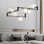 The Clérachic Ostruvye lit above a pale sofa dressed in olive cushions, a sheer curtain drawn behind it.
