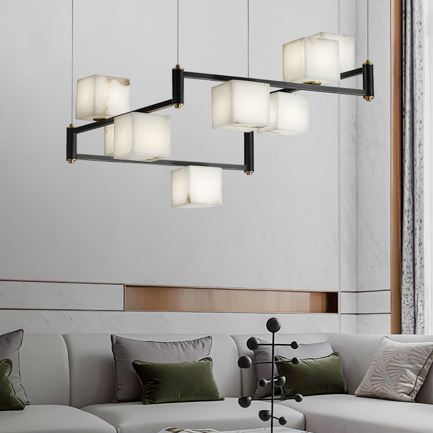 The Clérachic Ostruvye lit above a pale sofa dressed in olive cushions, a sheer curtain drawn behind it.