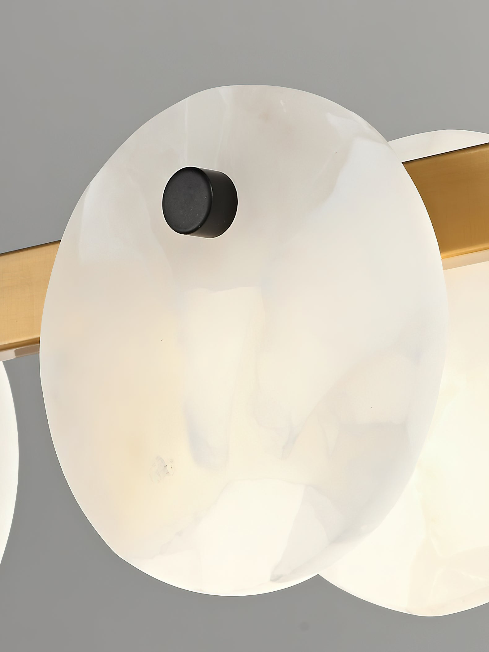 A single veined alabaster disc on the Clérachic chandelier, pinned to the brass ring by a small dark stud.