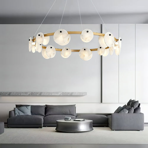 The Clérachic chandelier hung over a grey sectional sofa, its brass ring floating in a pale open living room.