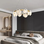 Clérachic chandelier above a low bed in a bedroom of dark timber panelling, alabaster discs catching the light.