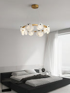 Clérachic chandelier over a black platform bed, daylight from a sheer-curtained window washing the alabaster.