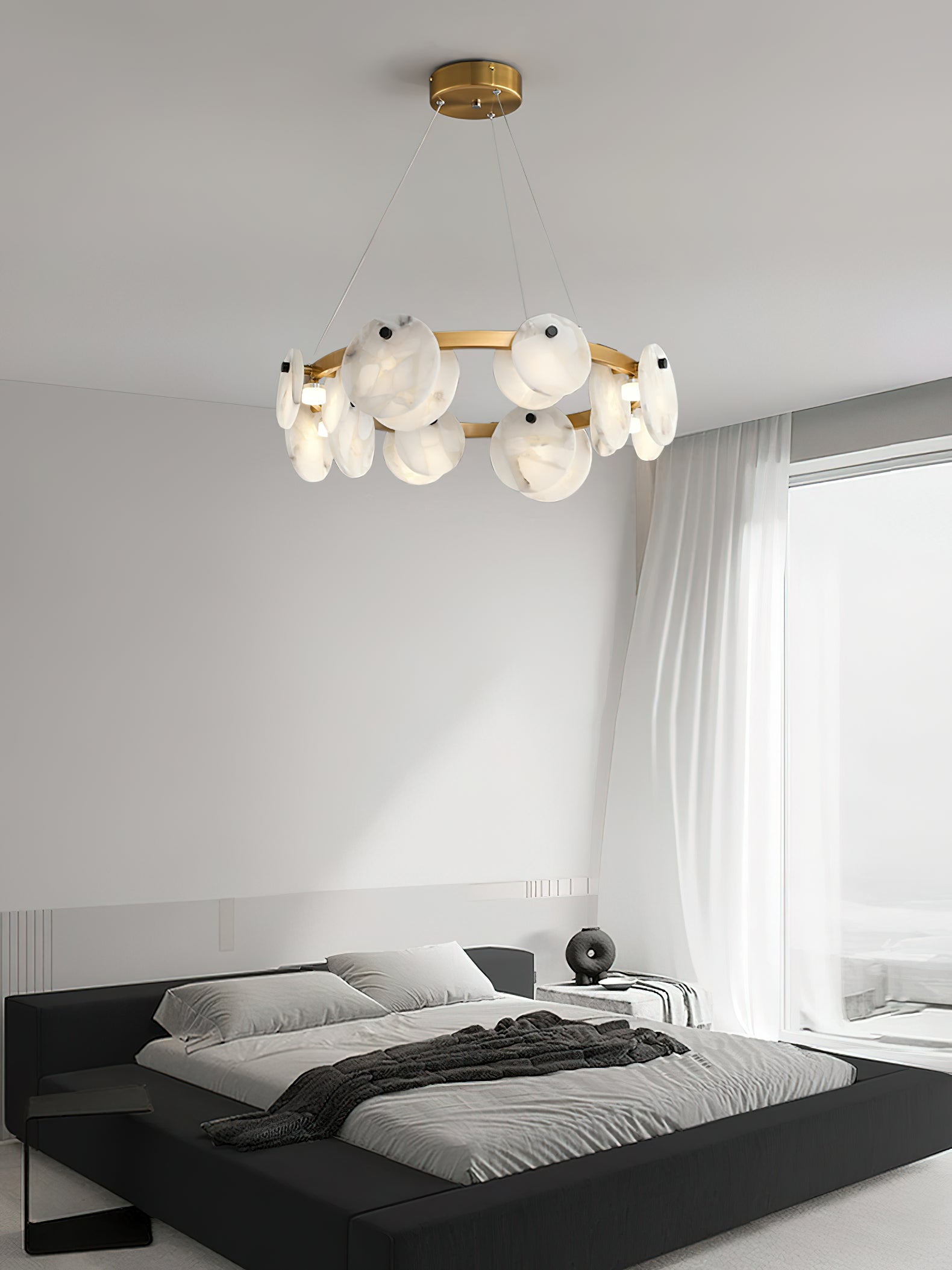Clérachic chandelier over a black platform bed, daylight from a sheer-curtained window washing the alabaster.