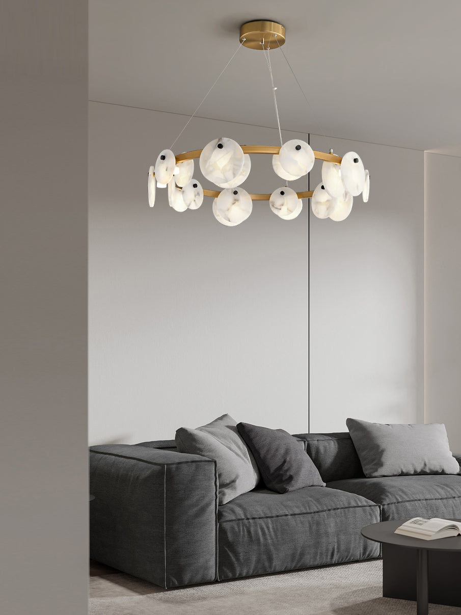 The Clérachic chandelier seen from a doorway, hanging above a deep grey modular sofa in a calm living room.