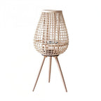 Clérachic tall teardrop lantern in pale woven cane on three tapered wooden legs, with a candle space inside.