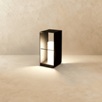 Clérachic medium black lantern with a lit white cylinder inside an open frame, casting a warm pool of light on the floor.