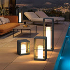 Clérachic dark lanterns in three heights glowing beside a terrace pool, with sun loungers and an orange sofa at dusk.