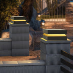 Two Clérachic post lights glowing warm on ribbed grey pillars beside a garden path at dusk.