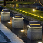 Three Clérachic post lights stepping down a pool edge at night, each casting a warm yellow band.