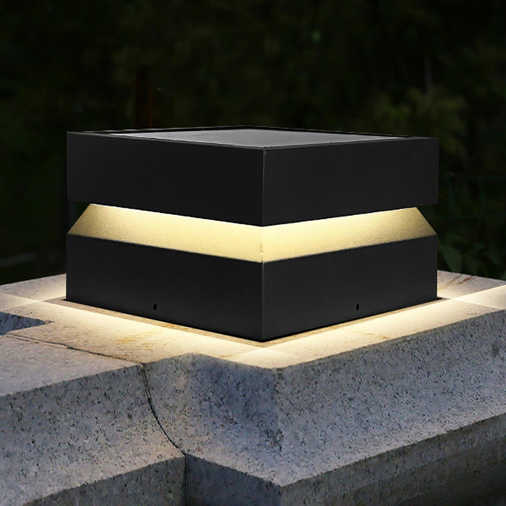 Close view of a Clérachic square post light lit on a stone corner, the warm band glowing under the lid.