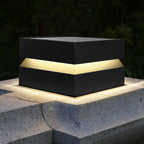 Close view of a Clérachic square post light lit on a stone corner, the warm band glowing under the lid.