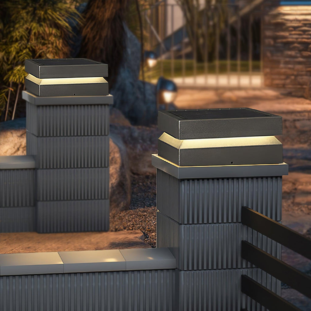 Ribbed pillars topped with Clérachic post lights, their warm bands glowing against a dusky garden.
