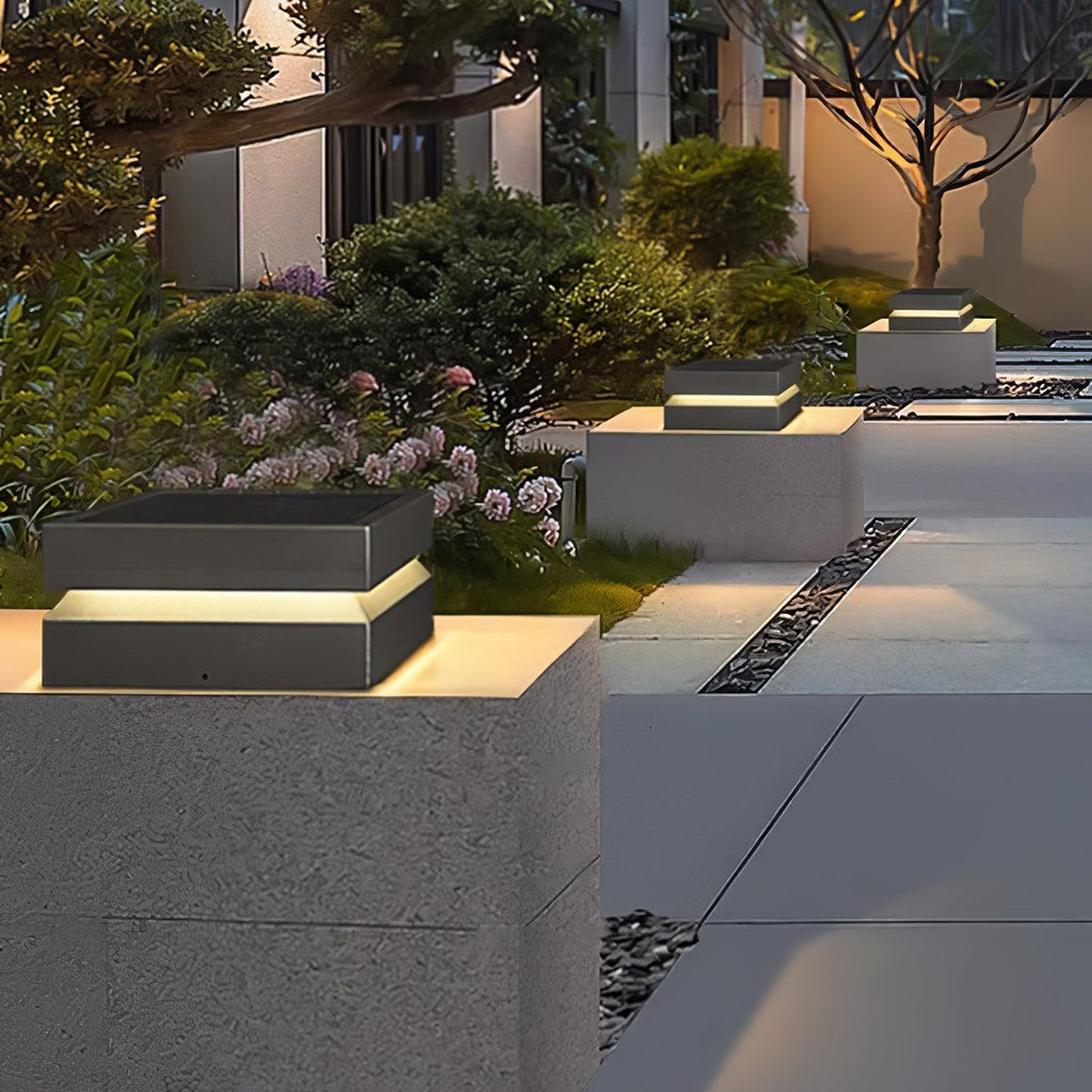 Beside a paved path, a Clérachic post light on a concrete pier lights the planting and stepping stones.