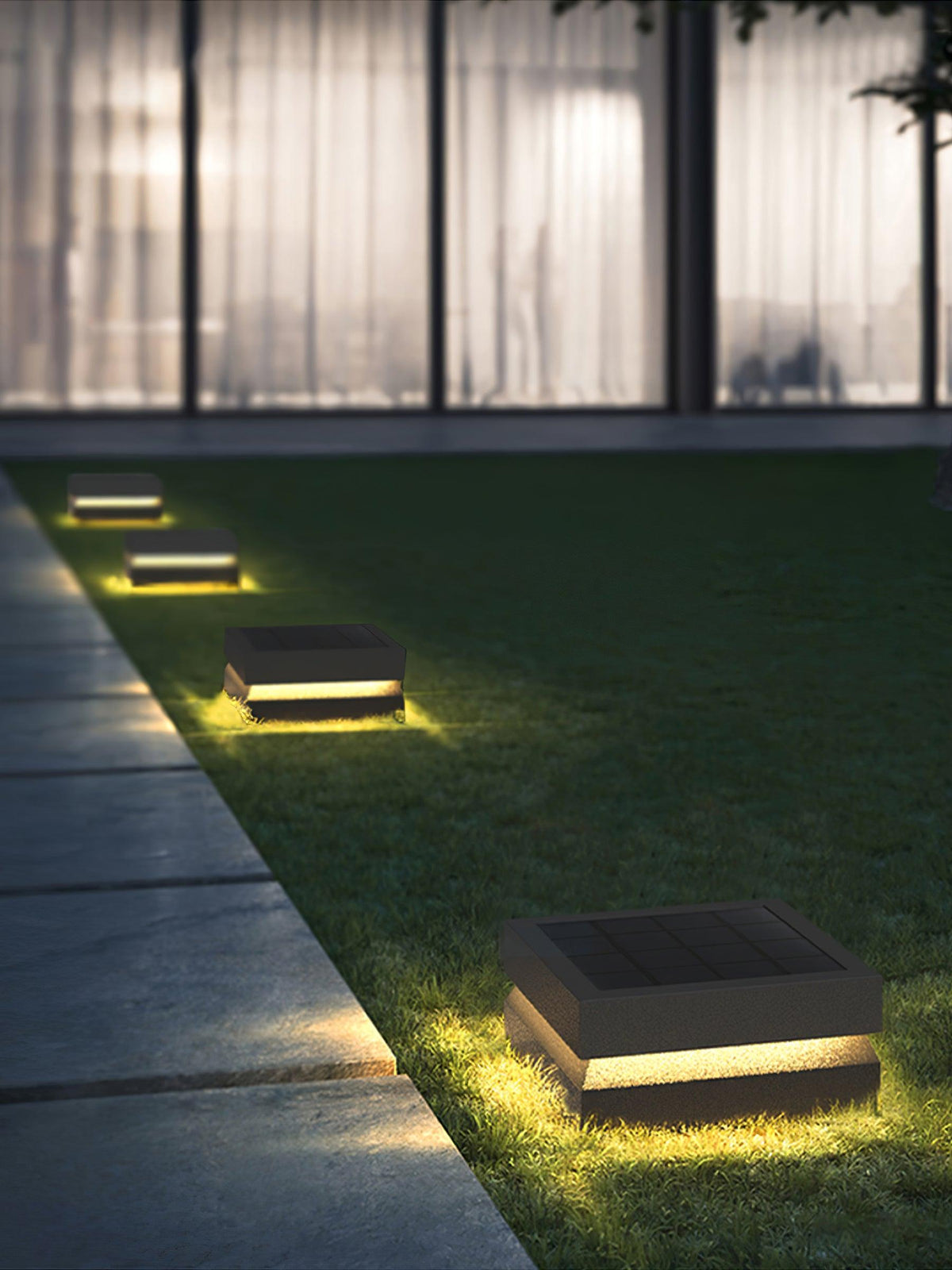 Clérachic post lights follow a stone path across a lawn at night, each with a warm glowing band.