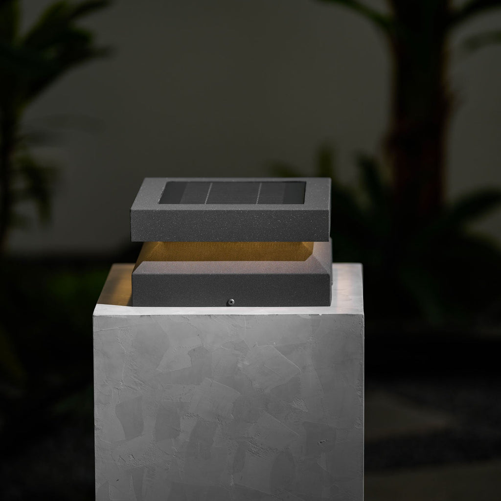 Unlit Clérachic post light on a pale stone block against a dark leafy background, solar panel facing up.