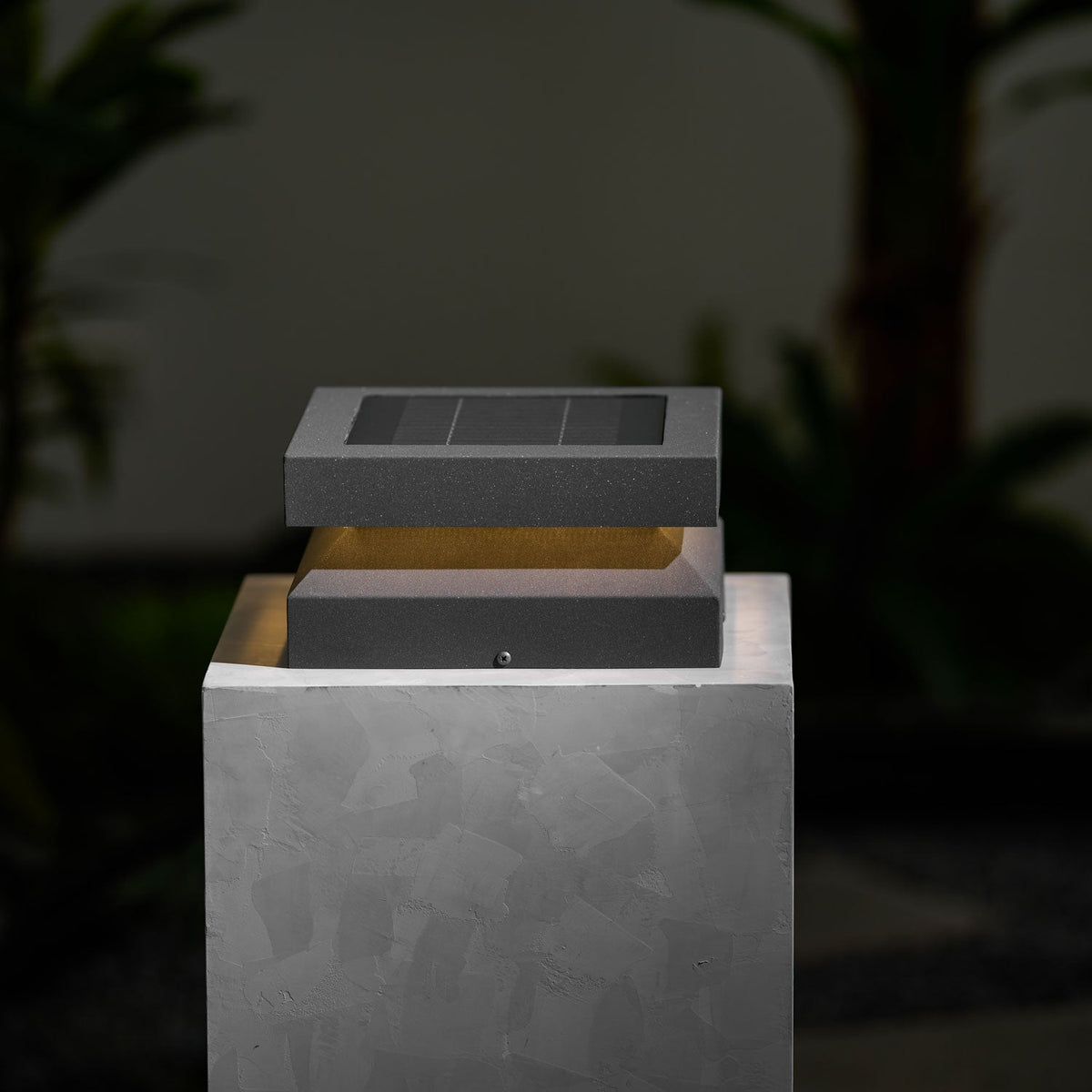 Unlit Clérachic post light on a pale stone block against a dark leafy background, solar panel facing up.