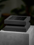Unlit Clérachic post light on a stone block, its dark lid turned slightly over the base with a small screw.
