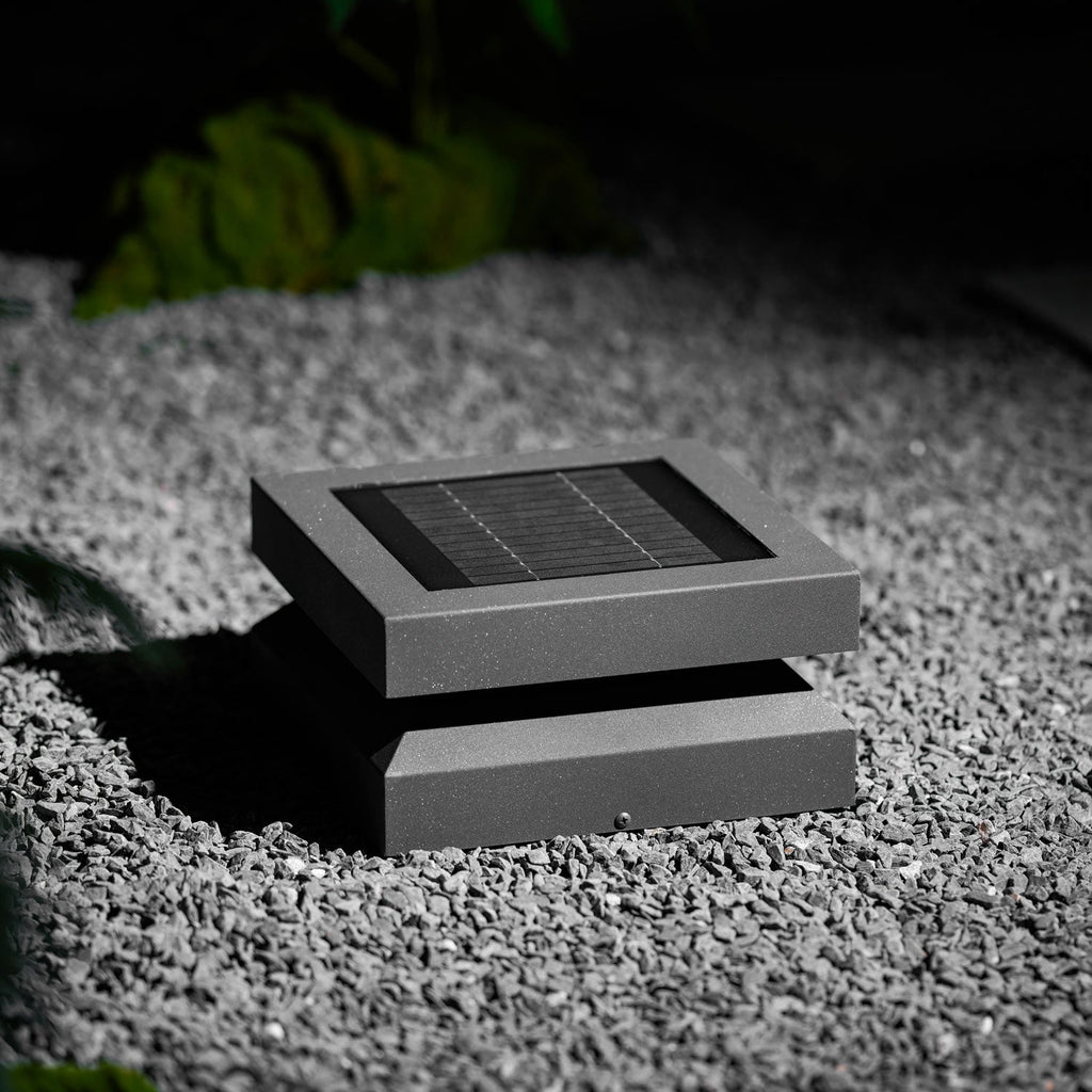 Closer view of a Clérachic post light on gravel, the framed solar panel and angled base clearly visible.