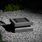 Closer view of a Clérachic post light on gravel, the framed solar panel and angled base clearly visible.
