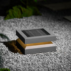 Clérachic post light on gravel lit warm, the amber glow showing between the solar lid and base.