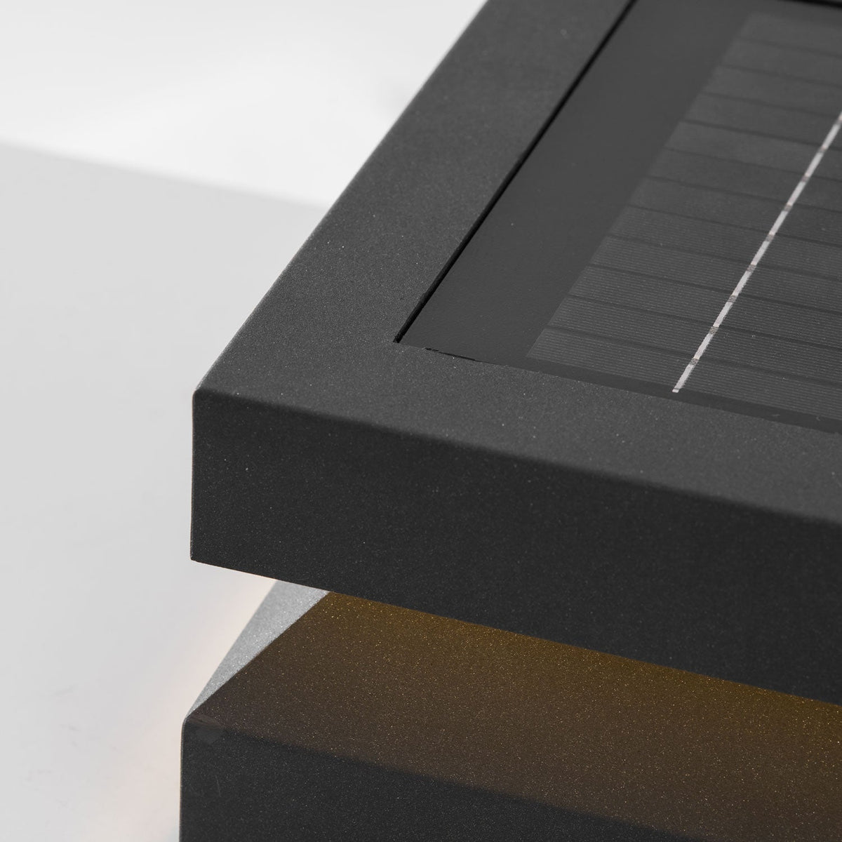 Close view of a Clérachic post light corner, with the solar panel's fine grid and a sandblasted metal edge.