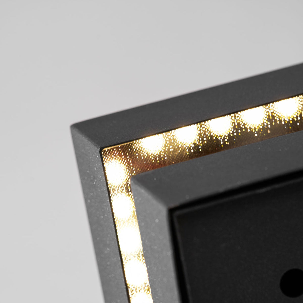 Macro view inside the gap of a Clérachic post light, a row of small LEDs lining the metal edge.