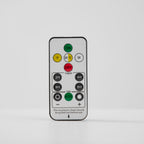 Remote control with on, off, timer and dimming buttons, shown on a pale grey backdrop for this Clérachic light.