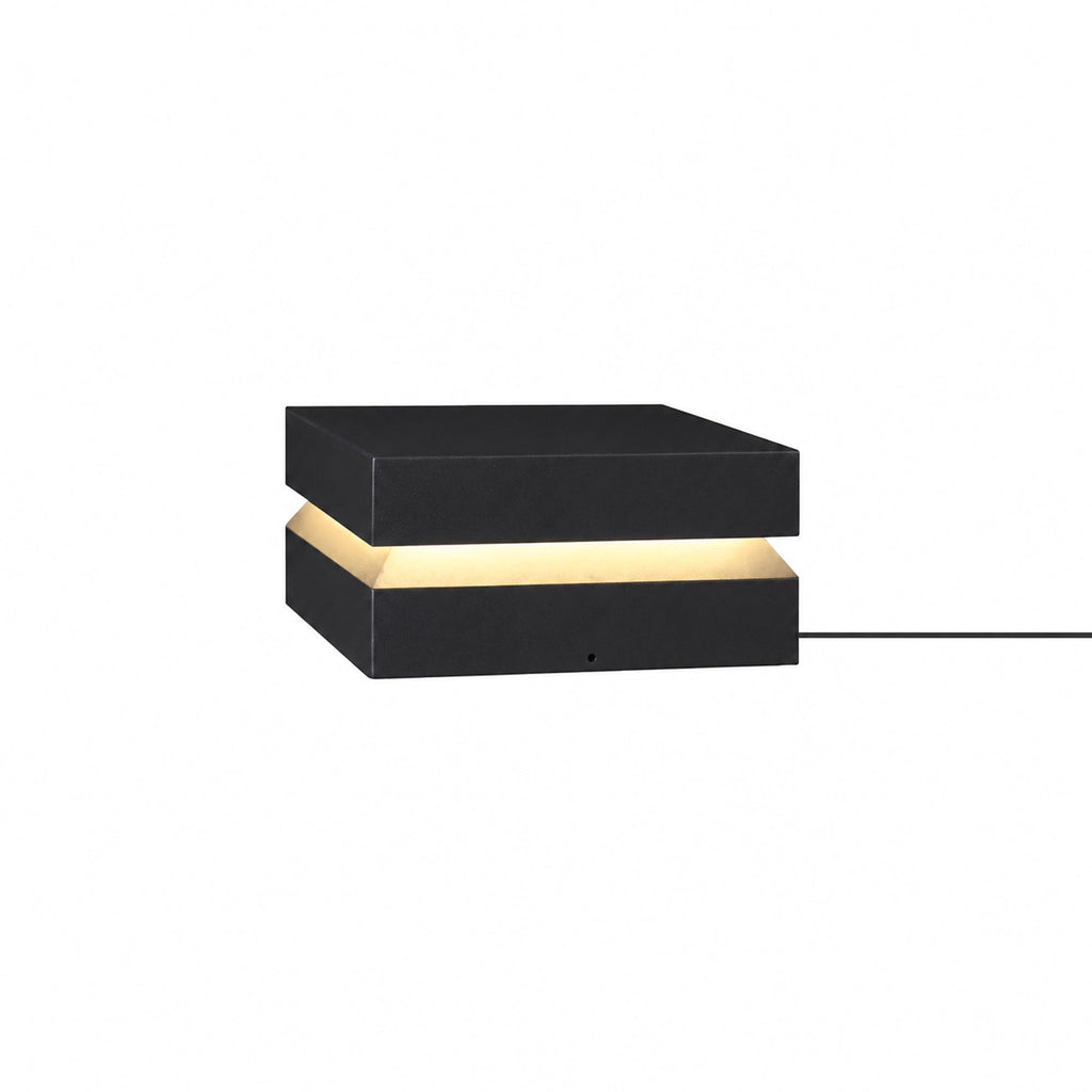 Black Clérachic post light on white, a warm band between lid and base and a cable at the right.