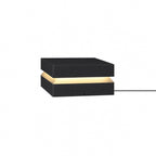 Black Clérachic post light on white, a warm band between lid and base and a cable at the right.