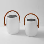 Two Clérachic lanterns, one larger than the other, side by side and unlit on a white surface, handles raised.