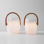 Pair of Clérachic lanterns in two sizes, switched on, the warm light filling the lower part of each white body.