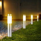 Clérachic row of silver stainless-look solar path lights with frosted bands, glowing warm along a gravel and lawn edge.