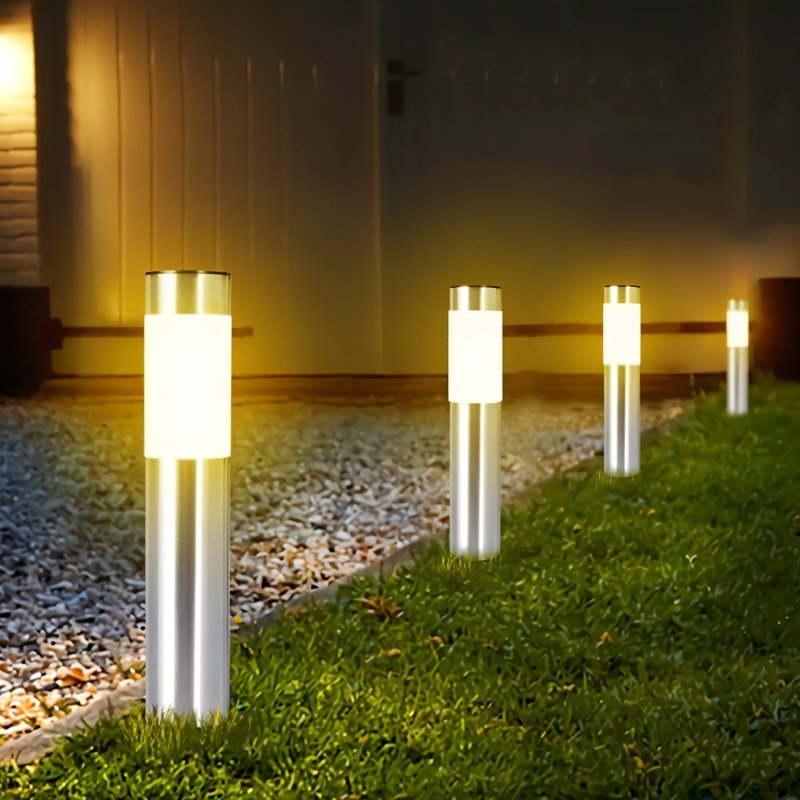 Clérachic row of silver stainless-look solar path lights with frosted bands, glowing warm along a gravel and lawn edge.