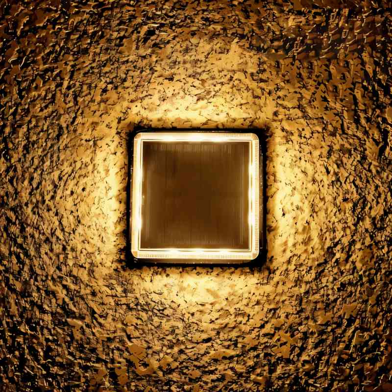 Top-down view of a Clérachic square solar light glowing warm, set into rough stone with a dark panel at its centre.