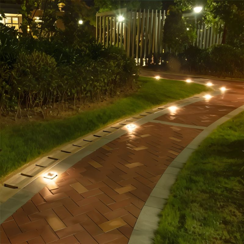 Clérachic solar lights set along the edge of a brick-paved path at night, each giving a small warm glow.