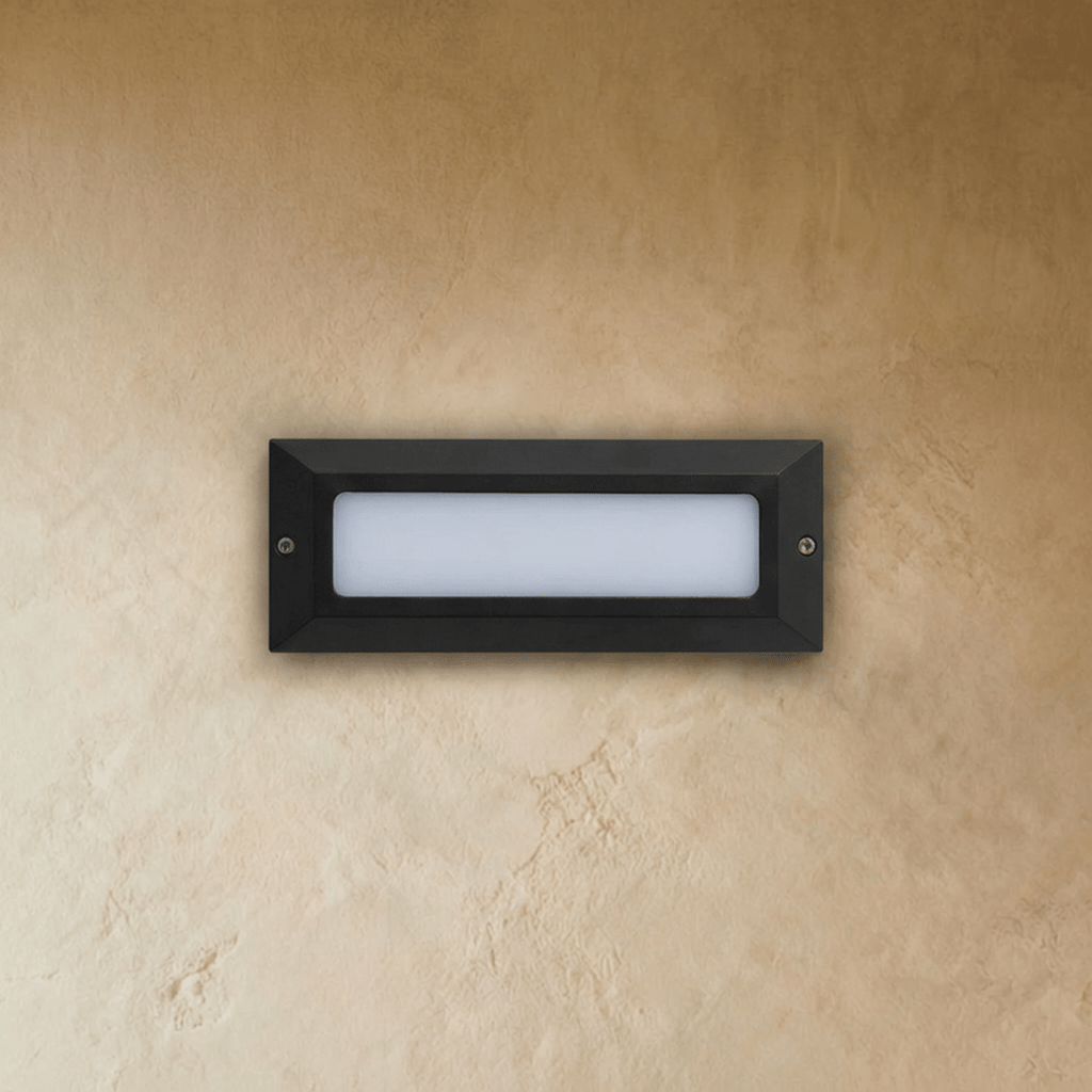 Clérachic small rectangular step light in dark grey with the frosted diffuser unlit, two fixing screws on a plaster wall.