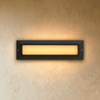 Clérachic large rectangular step light in dark grey with a long frosted panel glowing warm white on a plaster wall.