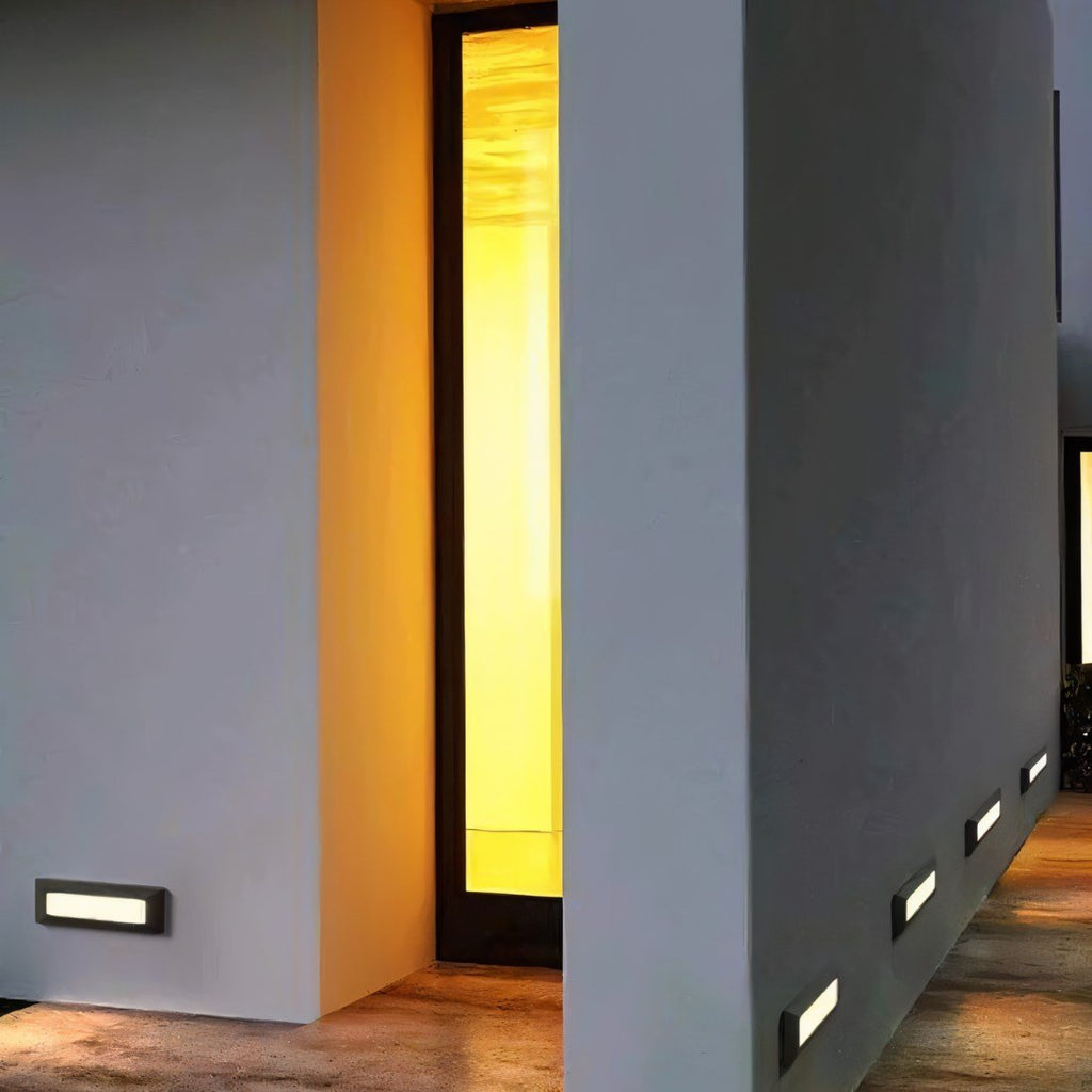 Clérachic low-level step lights glowing along a rendered wall and walkway beside a lit doorway at dusk.