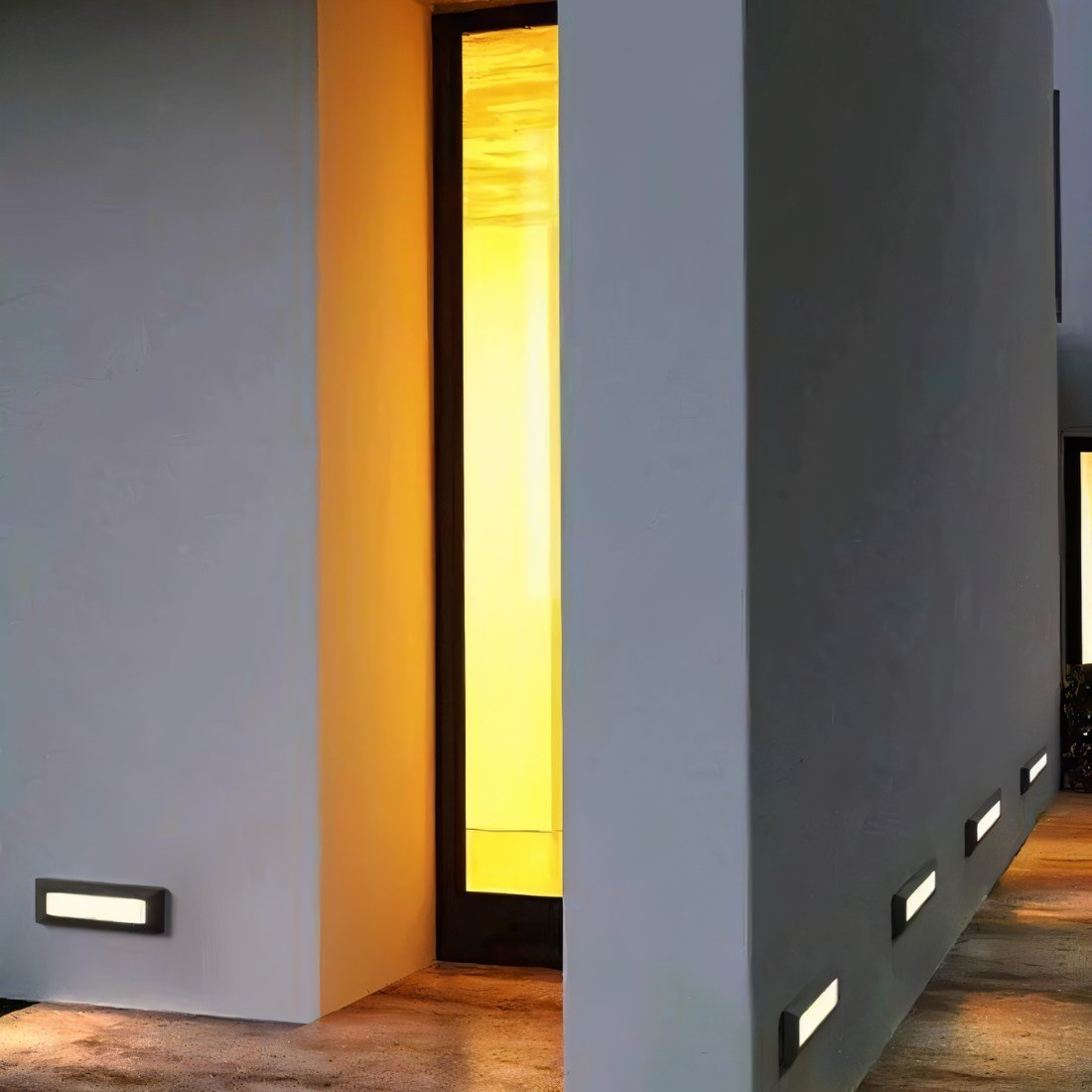 Clérachic low-level step lights glowing along a rendered wall and walkway beside a lit doorway at dusk.