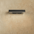 Clérachic short black aluminium bar wall light switched off against a limewashed wall, with the sensor on its bracket.