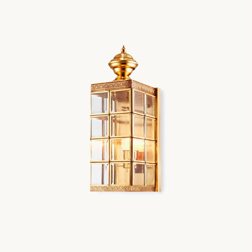 This Clérachic brass outdoor wall light on a plain white backdrop, a gridded glass lantern body under a turned brass finial.