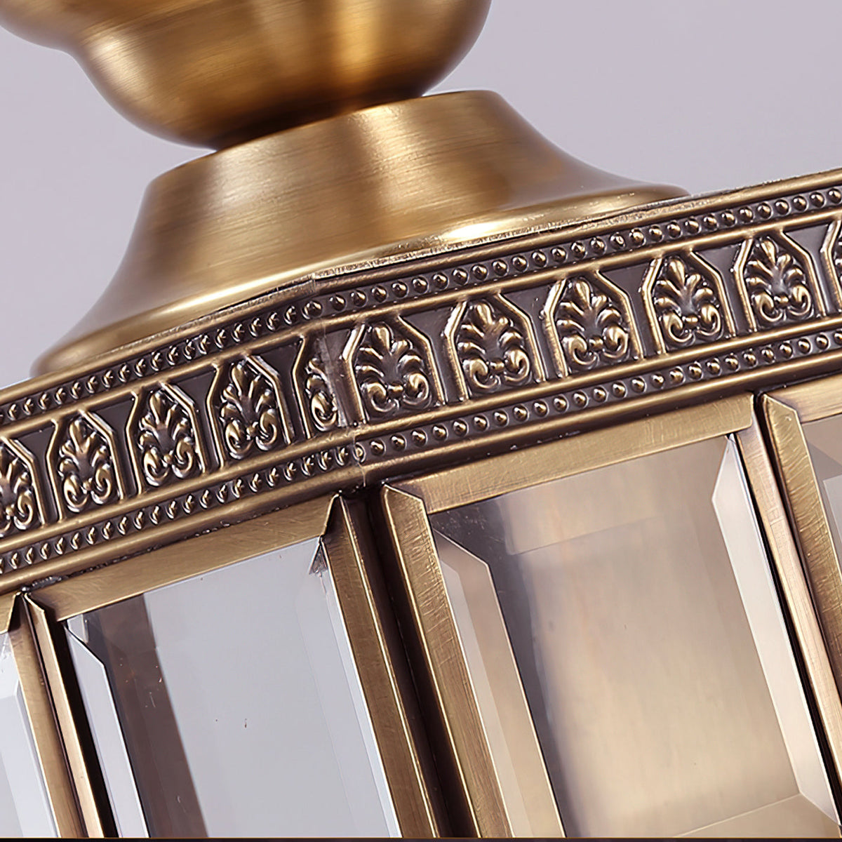 Close view of the brass finial base, the etched border and the bevelled glass panes on this Clérachic wall light.