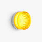 Round glass wall light with rippled concentric rings glowing yellow, on a plain white backdrop, from Clérachic.