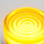 Close view of the rippled concentric glass face of this Clérachic wall light, glowing in a vivid yellow.