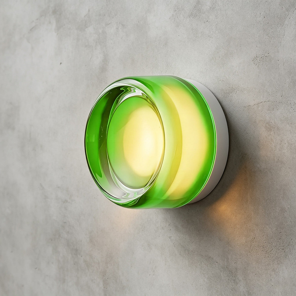 Green glass version of this Clérachic wall light with a clear central lens, casting a soft glow on a concrete wall.